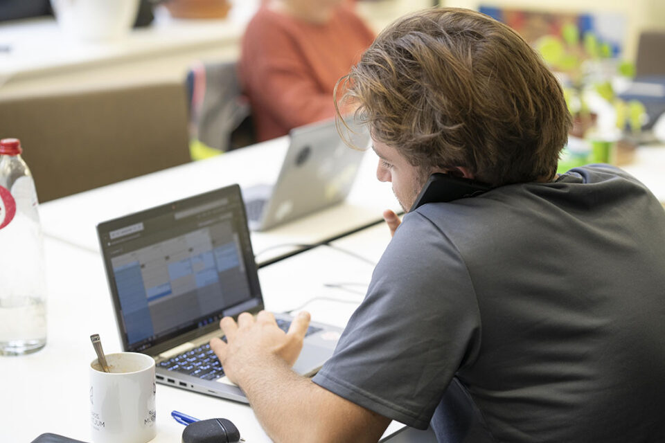 Werknemer zit aan zijn laptop en is tegelijkertijd aan het bellen